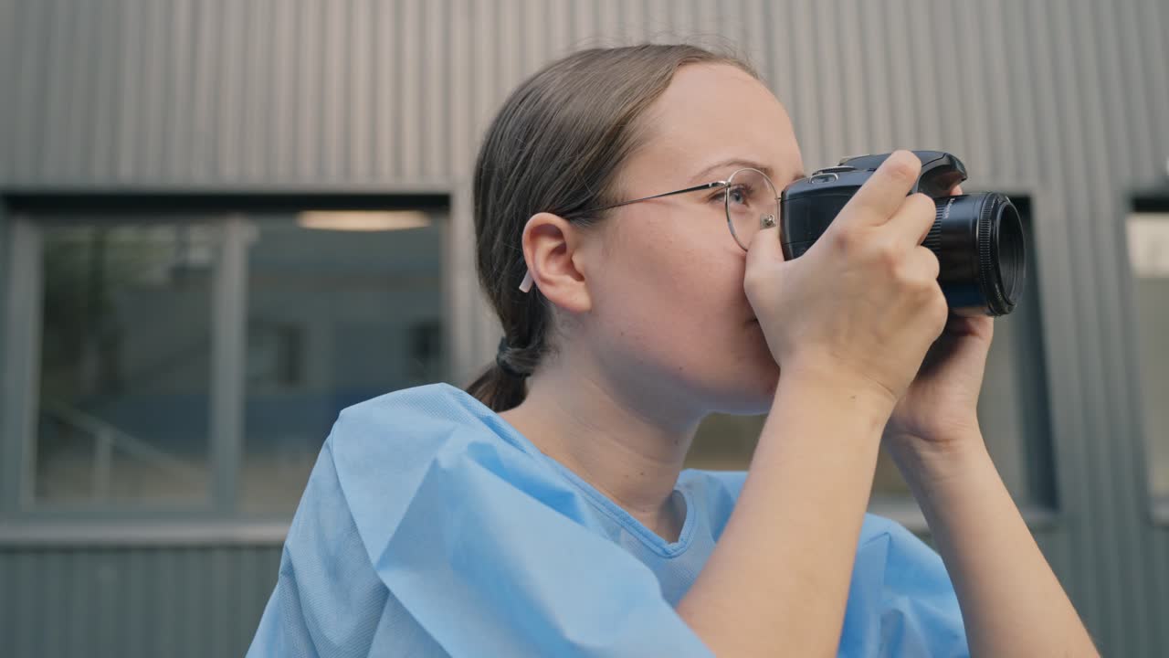 젊은 여성 의사가 병원 방 안에서 카메라로 사진을 찍고 있습니다.