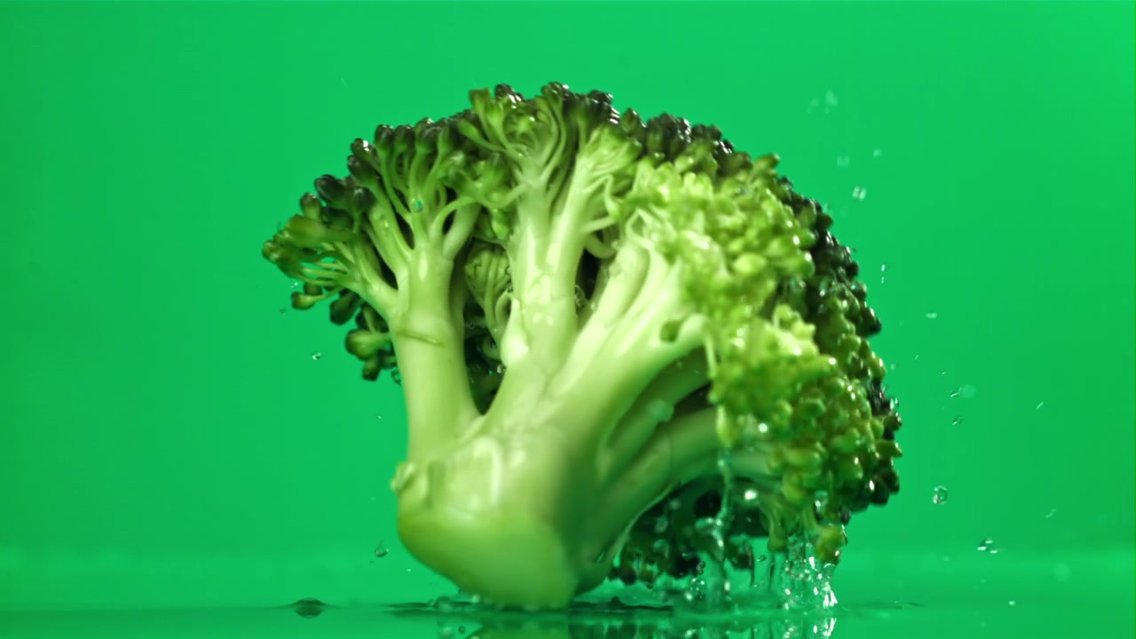 Fresh Broccoli Falling into Water with Splashes on Green Screen