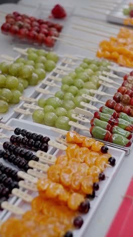 close up view of fresh and delicious asian japanese sweets called tanghulu, made with sugar coated tangerines, grapes and berries in a street food market.
