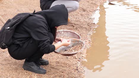 person panning for gold by the water