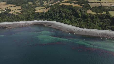 coastal scene showing the lemuy island shoreline with scenic greenery and blue waters. aerial pull back shot