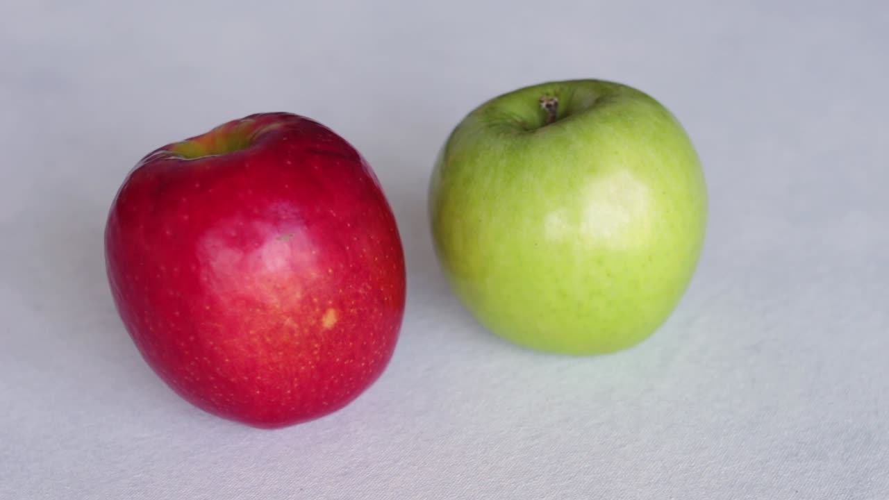 Hånd lægger røde og grønne æbler på bord