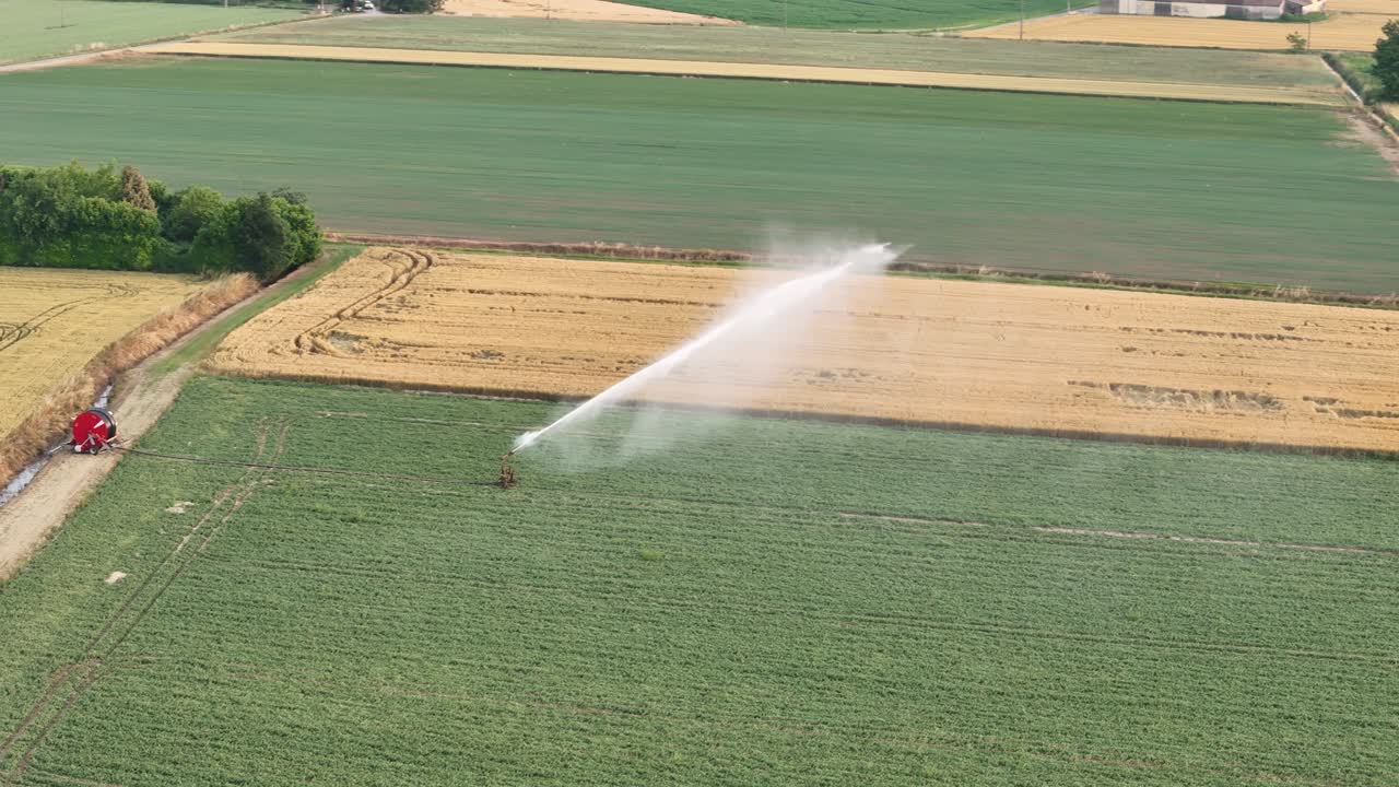 Sofisticato sistema di irrigazione che spruzza acqua sui campi di soia nella Pianura Padana, fornendo idratazione mirata con irrigatori di precisione durante la rigogliosa stagione di crescita primaverile, con un drone in orbita