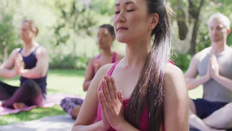 Group-of-diverse-young-people-meditating-and-practicing-yoga-together-at-the-park