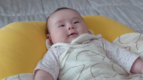 infant baby daughter smiling while lying on a comfortable cushion in the room