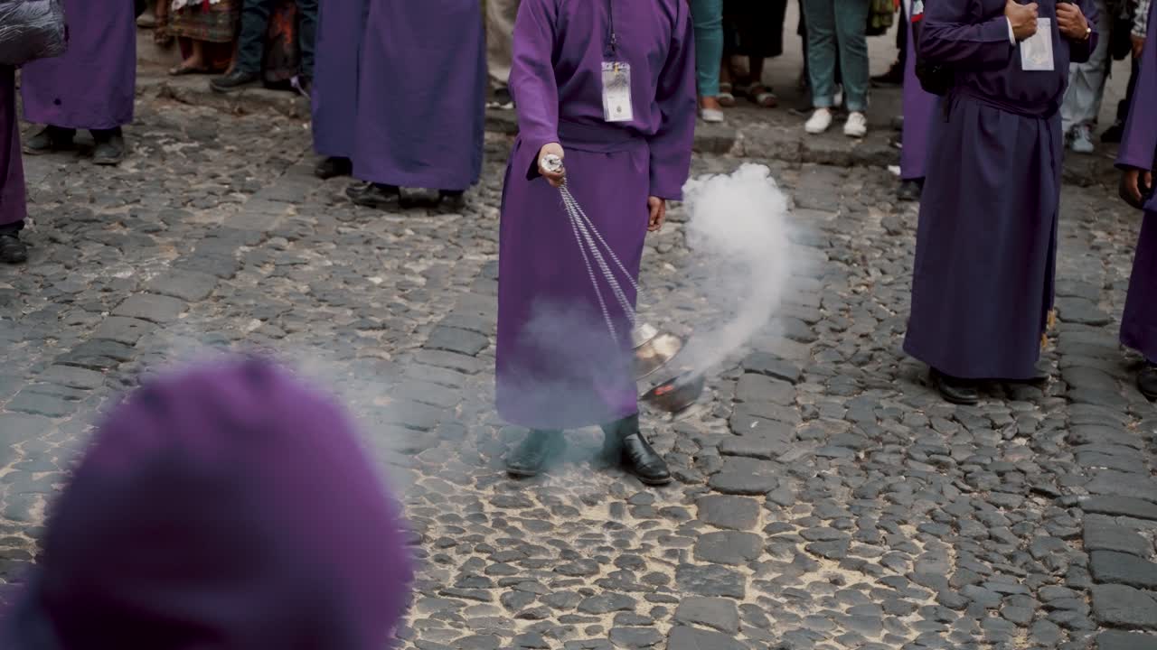 hombre con túnica de lila con incienso durante las procesiones de la semana santa en antigua guatemala