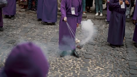 man in lilac robe with incense during semana santa processions in antigua guatemala