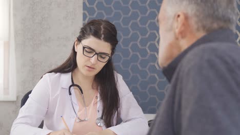 young female doctor in white uniform and stethoscope on her neck talking to elderly patient.