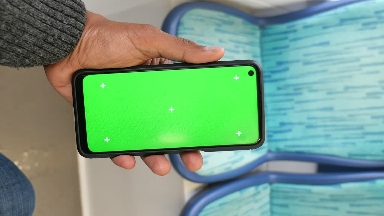 Person holding phone with green screen on a bus