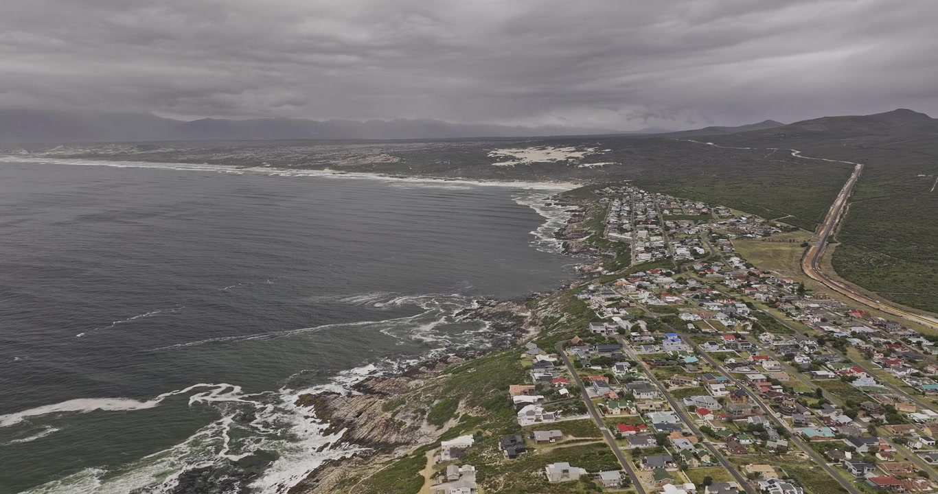 Gansbaai, Jižní Afrika, letecký přelet v7 podél pobřeží De Kelders a rezidencí vedle přírodní rezervace Walker Bay pod zataženou oblohou – Pořízeno s Mavic 3 Pro Cine – 7. ledna 2024.