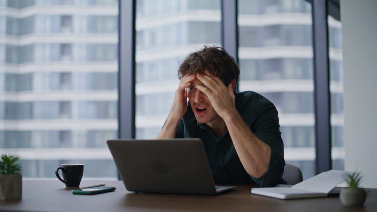 Stressed loser reading laptop bad news at contemporary workspace closeup