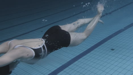 unterwasseraufnahme einer jungen schwimmerin, die in den pool springt und hineintaucht