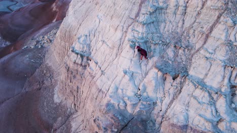 person-carefully-and-slowly-climbing-down-a-large-rock-formation-in-the-mesa-of-bentonite-hills-in-hankesville-utah