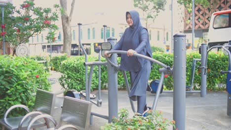 Junge-Asiatische-Muslimin-Im-Hijab,-Die-Morgens-Im-Fitness-Park-Air-Walking-Geräte-Benutzt