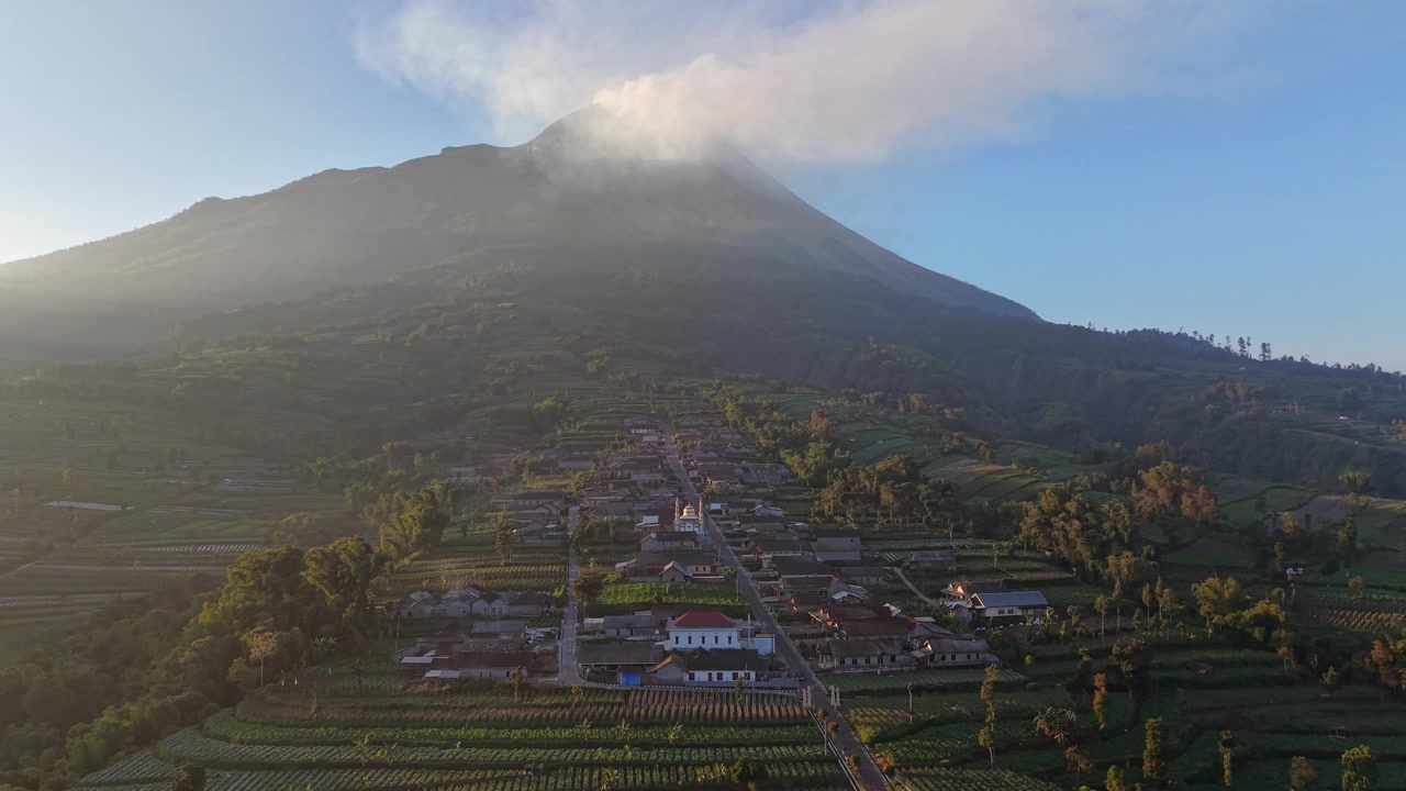 Spettacolare sfondo vulcanico che domina un tranquillo villaggio indonesiano. Il Monte Merapi e i campi fertili offrono una vista mozzafiato sulla campagna.
