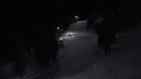 Aerial-of-snow-machine-at-work-in-Idre,-Sweden-during-a-late-evening-in-the-dark-6