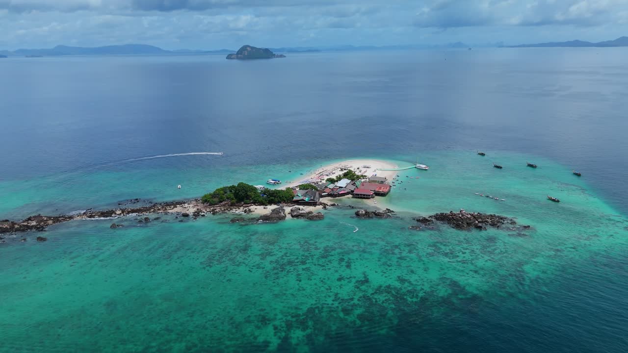 Drone orbits right jet ski passes the Khai Island sandbar with longtail boats over clear Andaman Sea water