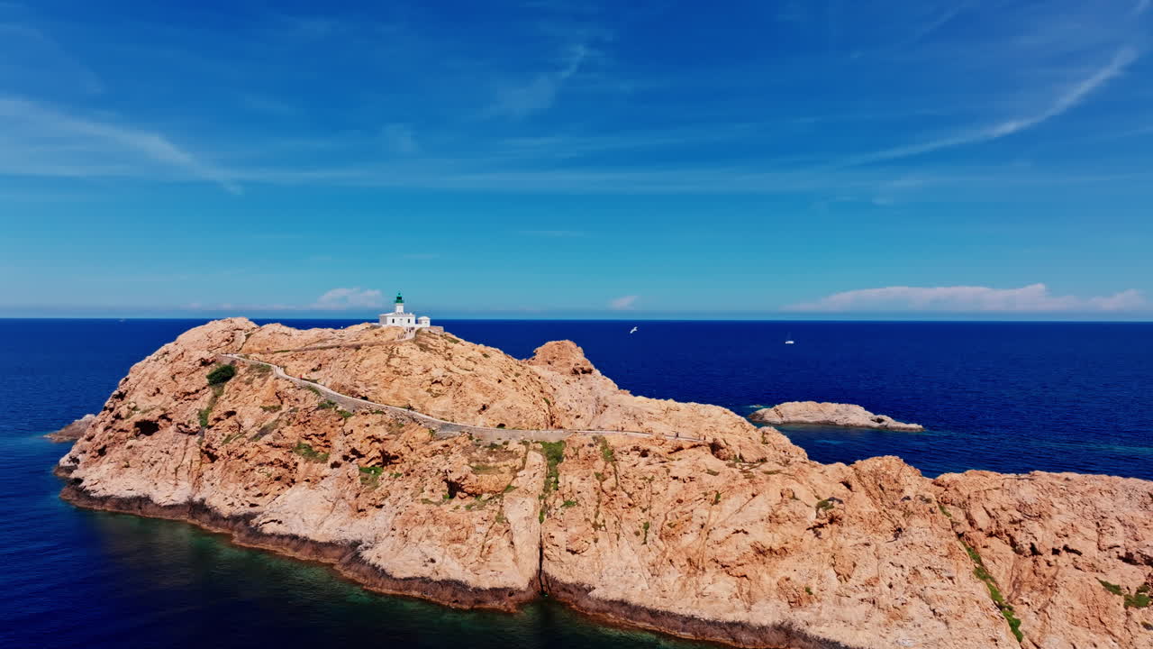 Aerial drone shot over Ile de la Pietra at the coastal town of Ile-Rousse in the Balagne region in Corsica, France. View of the White lighthouse on top of the cliff overlooking the landscape