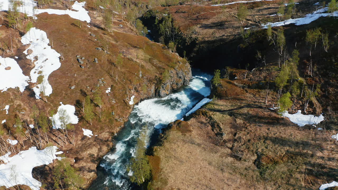 vista aérea con vistas a una cascada en la naturaleza nevada, soleado, día de verano, en los alpes de lyngen, norte de noruega - retroceso, disparo de drones