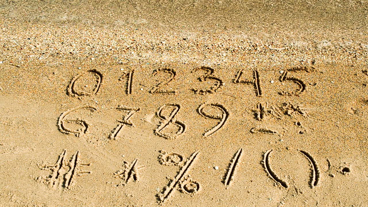 Cijfers en tekens geschreven in strandzand. Strandopname.