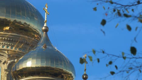 view of orthodox st nicholas naval cathedral golden domes and crosses on blue sky in sunny autumn day at karosta, liepaja, medium shot