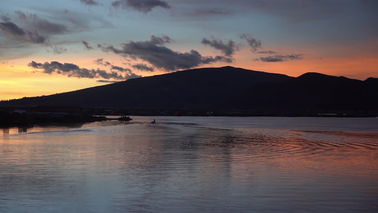 silueta de la bahía en las islas flotantes de los uros en el lago titicaca, al atardecer con un barco, tiro largo de lapso de tiempo