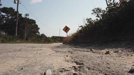 Cracked-Asphalt-Country-Road-Heading-To-Nauset-Lighthouse-In-Cape-Cod,-Massachusetts,-USA---Low-Level-Shot