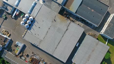 rising above the warehouse roof with the worker walking on. industrial plant with tops prepared for solar panel installing. top view.
