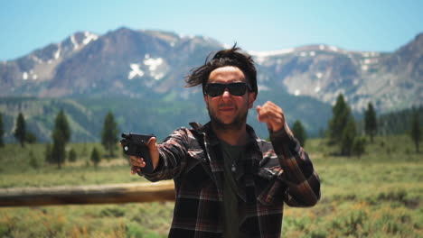 Caucasian-gunman-points-handgun-in-a-picturesque-mountain-range