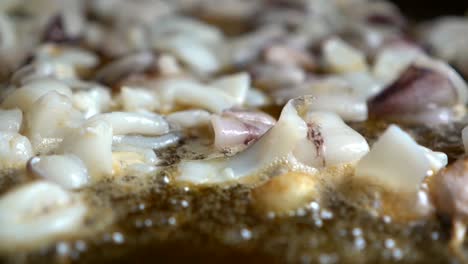 bokeh de calamar picado frito en aceite durante la preparación de una fideuá española