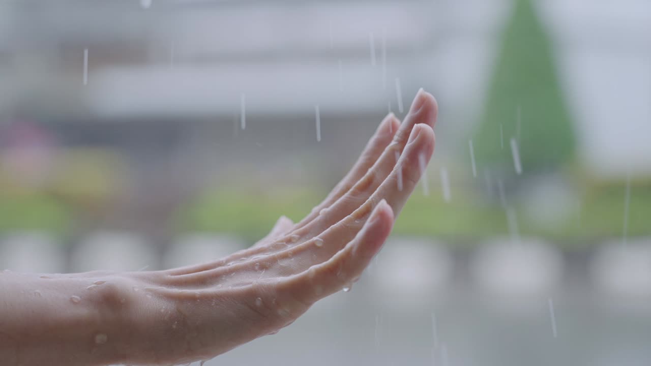 슬로모션으로 가까이 찍은 여성의 손은 작은 손바닥에 비를 즐겁게 잡고, 비가 오는 계절은 슬로 모션, 거리 쪽, 지구 온난화 개념, 표면 온도 및 습도가 습합니다.