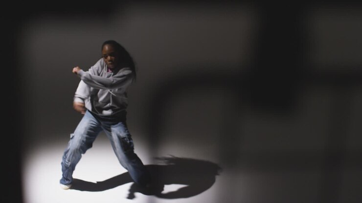Full Length Studio Portrait Shot Of Young Woman Dancer Dancing In Spotlight With Shadows In Foreground