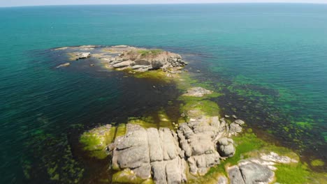 Fast-drone-flight-over-rocky-seashore-and-big-cliffs-in-sunny-summer-day