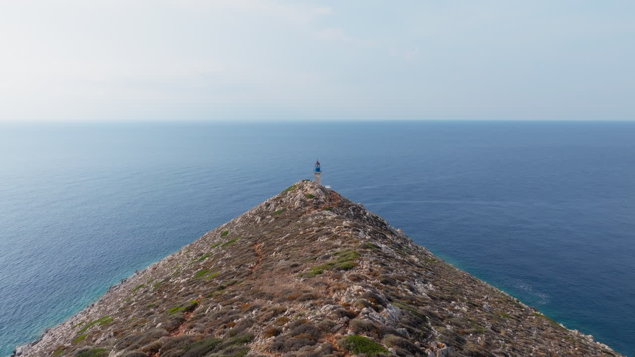 Aerial tracking shot reveals Cape Tainaron lighthouse closeup view on rocky coastline at the end of Mani Peninsula, Peloponnese, Mediterranean sea