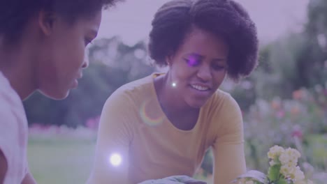 Spot-of-light-against-african-american-mother-and-daughter-gardening-together-in-the-garden