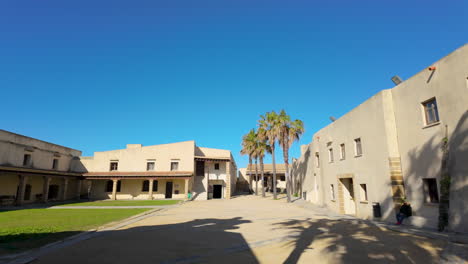 Framed by two towering cannons, this view captures the historic architecture of a courtyard in C&aacute;diz, complete with palm trees and clear blue skies