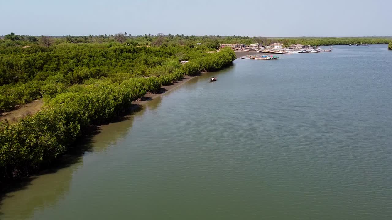 Góc nhìn từ trên cao ngược chiều sông Gambia với rừng ngập mặn, Kartong - Gambia cùng thuyền độc mộc và bầu trời xanh ở hậu cảnh.