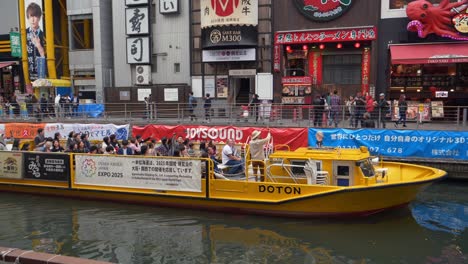 boat tours and city life on dotonbori canal in osaka, japan