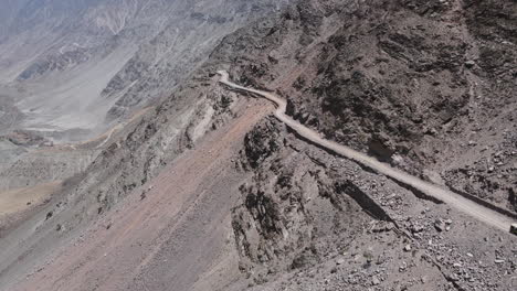 aerial view, dangerous hillside dirt road, rocky landscape of northern pakistan, drone shot