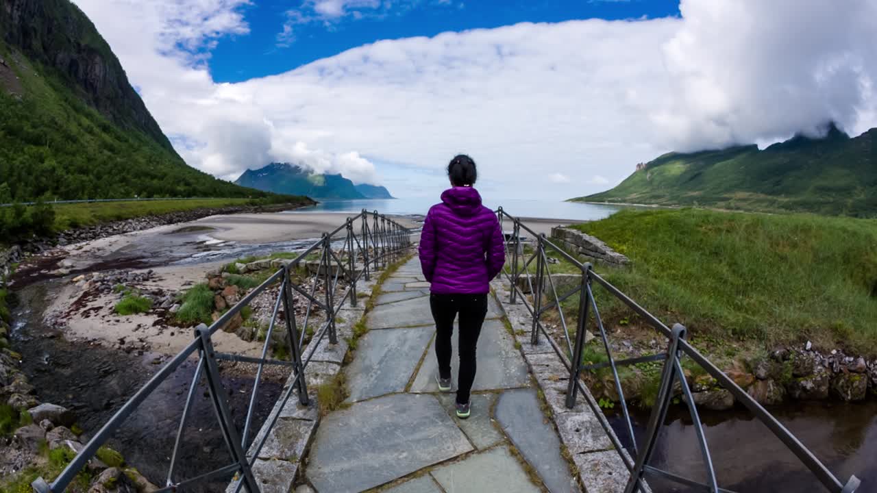 una mujer camina por un puente en medio de la hermosa naturaleza de noruega.