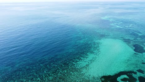 Aerial-seascape-view-of-stunning-crystal-clear-ocean-water-and-vast-coral-reef-ecosystem-in-Coral-Triangle,-Timor-Leste,-Southeast-Asia