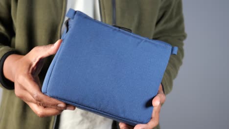 person holding a dark blue fabric pouch