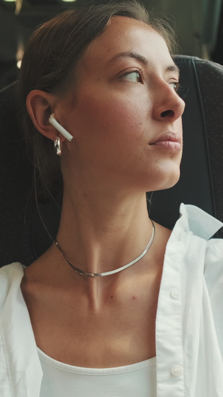 Giovane donna che ascolta musica con auricolari wireless mentre viaggia
