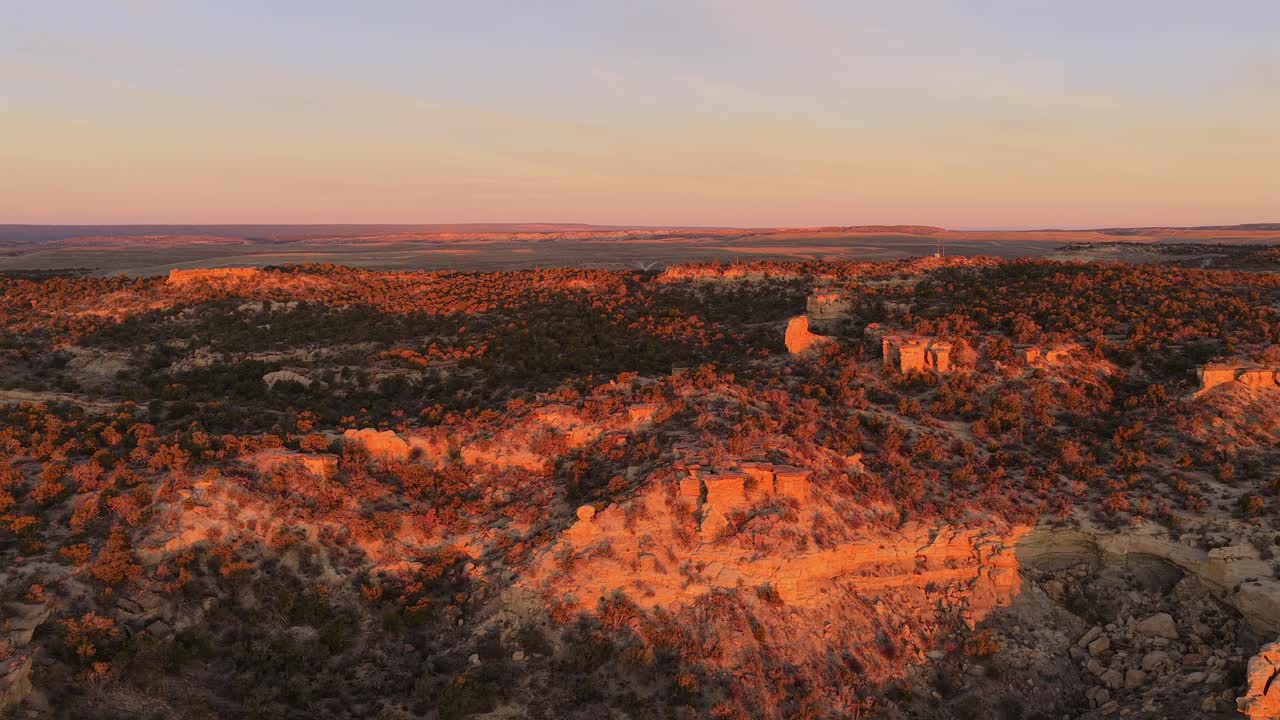 Une vue aérienne fluide par drone capture la douce lumière matinale et l'horizon coloré au-dessus d'un plateau désertique isolé. Ce paysage en 4K révèle la beauté sereine d'une aube du Sud-Ouest.