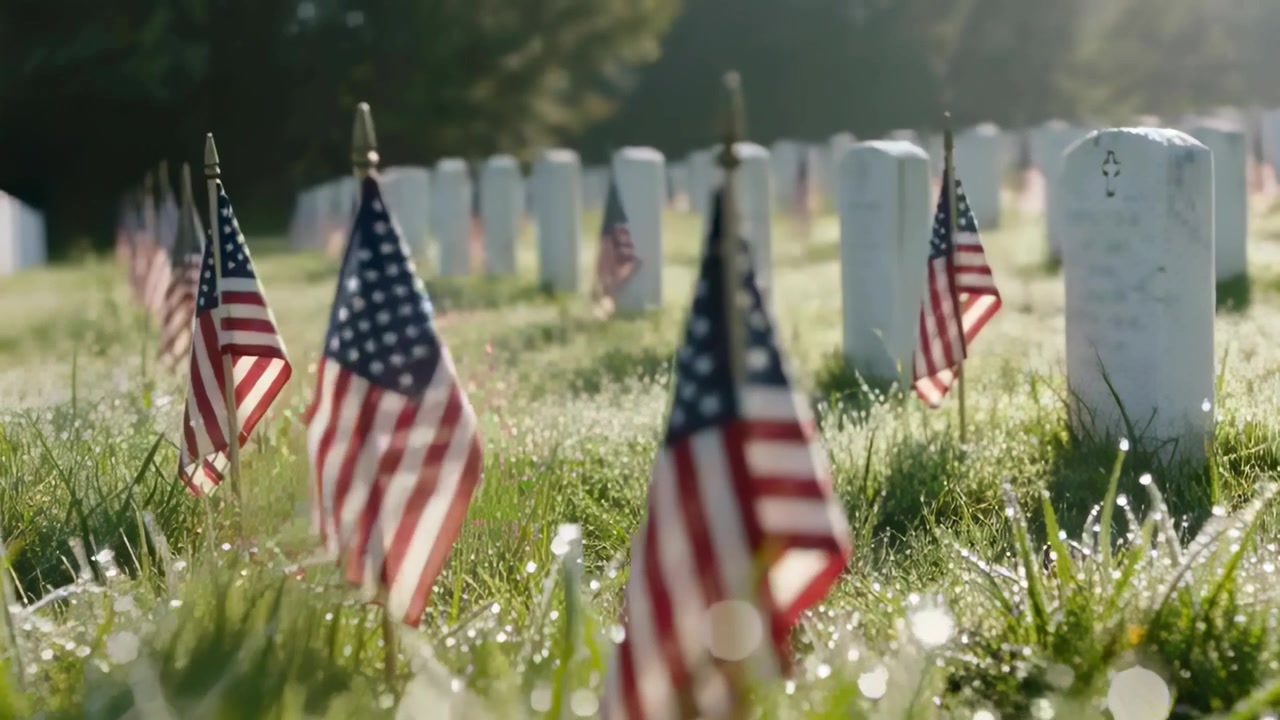 Gliding camera through cemetery grass with morning sun rising, revealing US flags and headstones