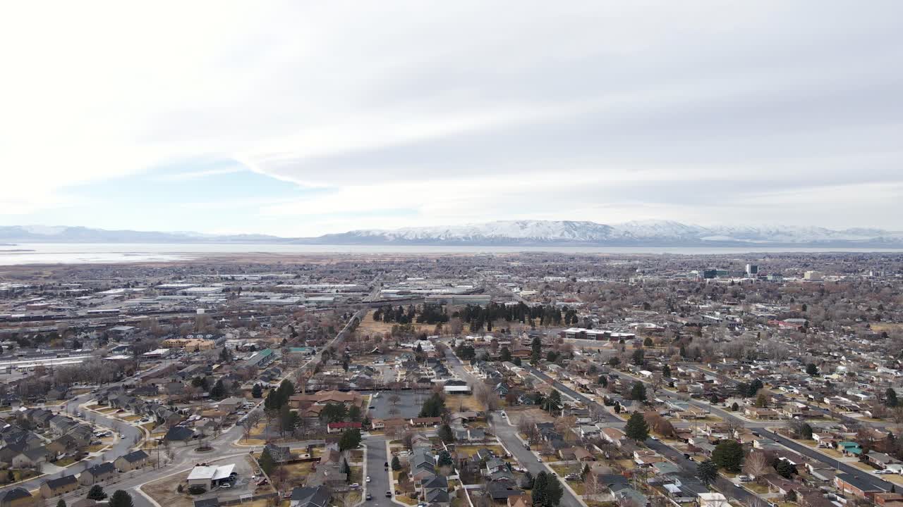 avance aéreo sobre la ciudad de provo en utah con montañas cubiertas de nieve en segundo plano.