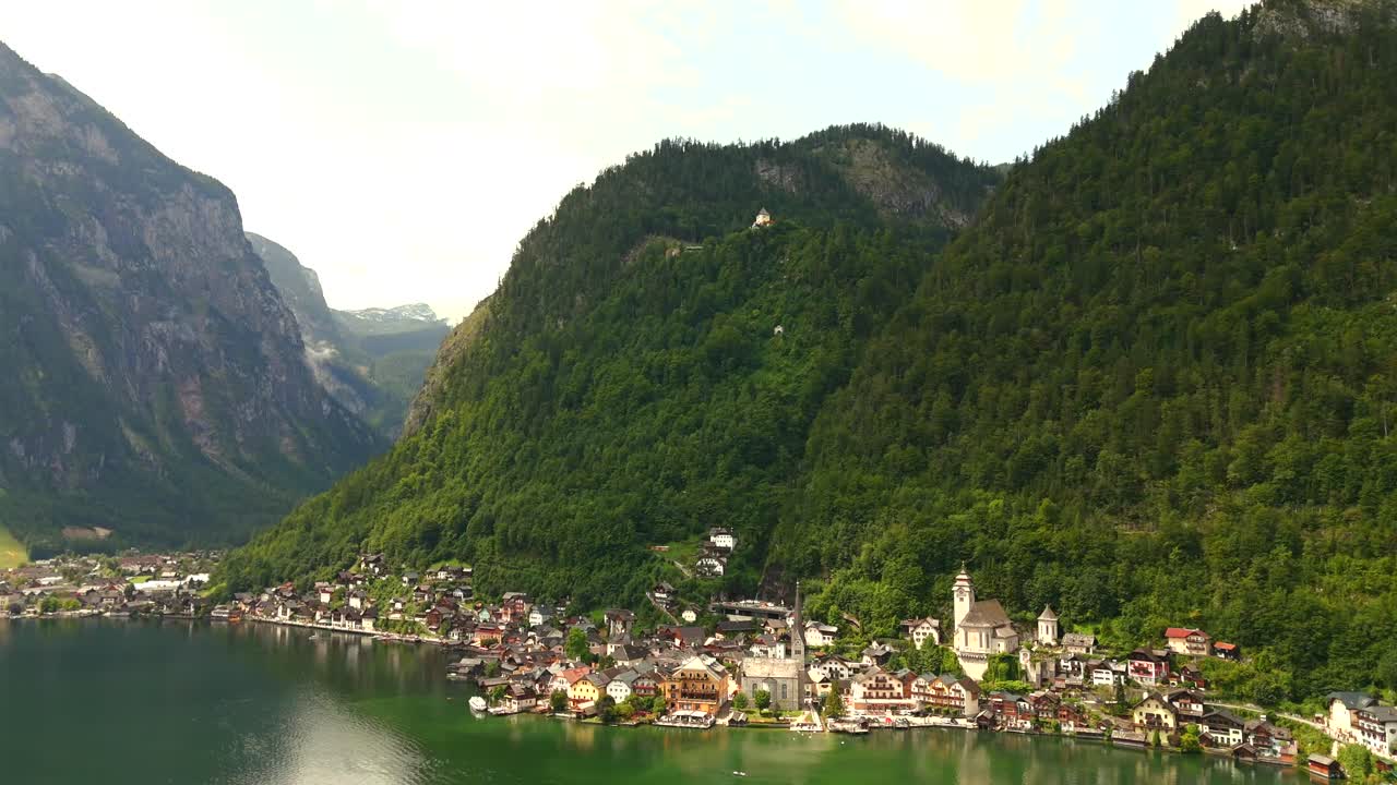 Aerial view of Hallstatt, Austria, captured by drone, showcasing its picturesque lakeside homes, majestic mountains, and the unique charm of this enchanting alpine village.