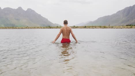 hombre caucásico pasando un buen rato en un viaje a las montañas, usando trajes de baño y saltando en