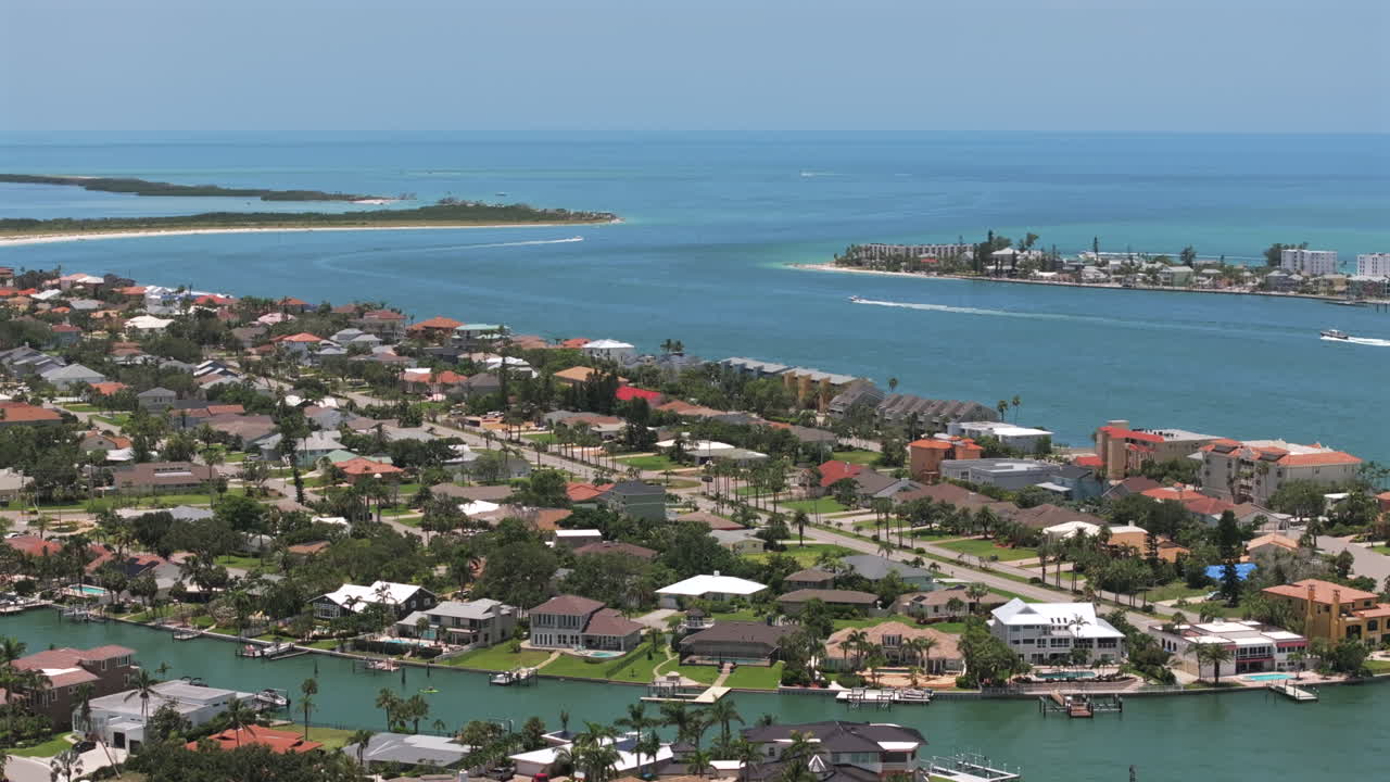 Drone shot of tropical St Petersburg, Florida waterfront homes and speeding boat on blue gulf pass-a-grille waters capturing serene coastal living, marina lifestyle, and scenic paradise by the ocean