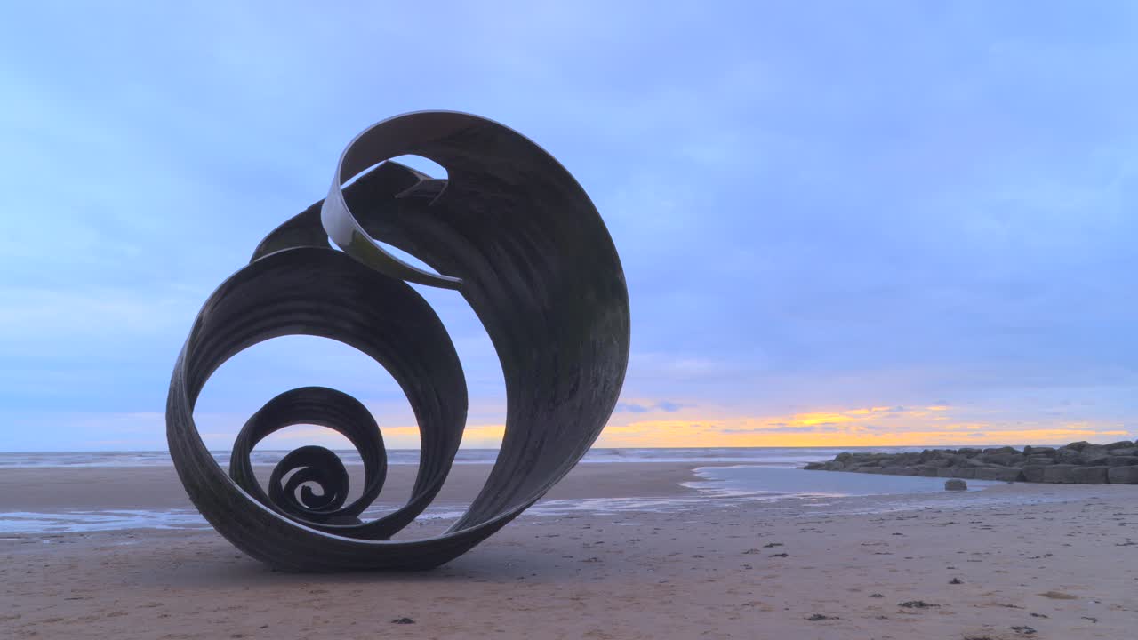 Stormy skies and incoming tide at beach with metal shell sculpture time lapse 60x at Mary's Shell, Cleveleys, Lancashire, England, UK